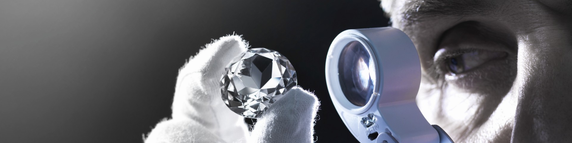 Man examines diamonds with a magnifying glass.