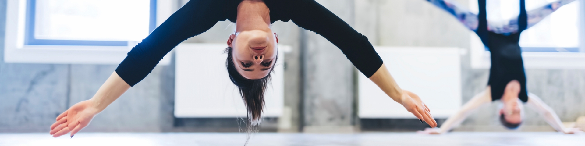 Frau macht eine Kopfstand-Yogaübung, in einem Seil kopfüber hängend